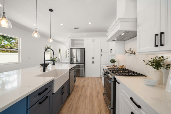 Bright, modern kitchen with white cabinets, marble countertops, a central island, and stainless-steel appliances.