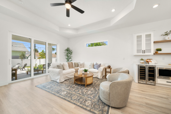 Bright living room with a large white sectional, round coffee table, and sliding glass doors to the patio outside.