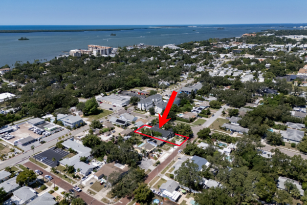Aerial view of a coastal suburban town with a red outline highlighting a residential property boundary at street level side.